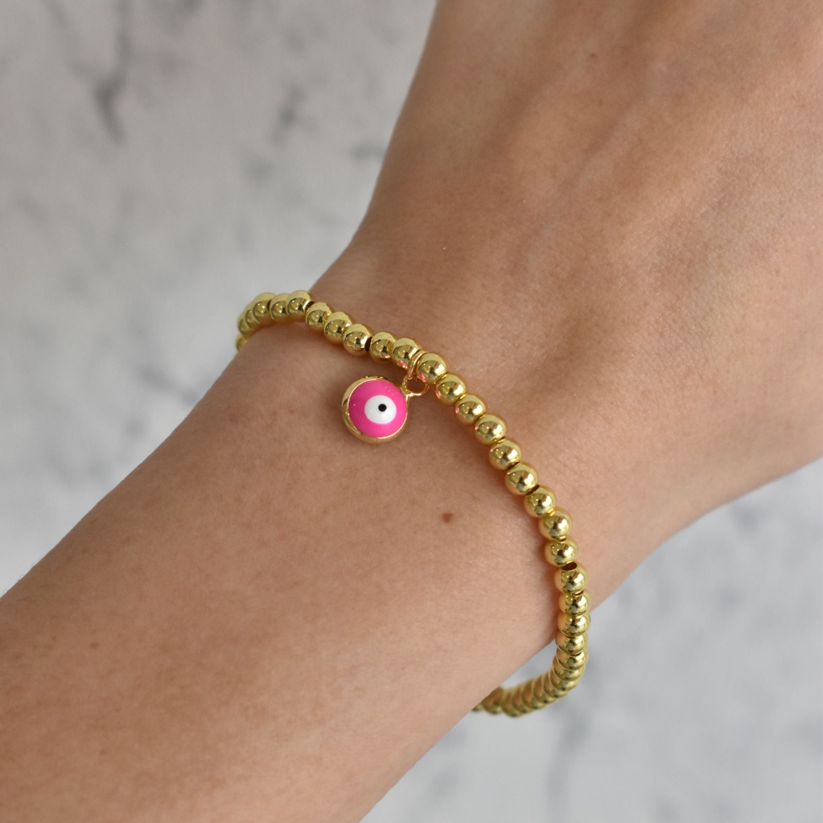 Pulsera bolitas doradas con ojo rosa